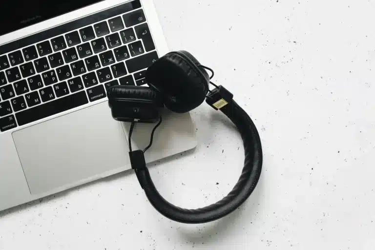 Gaming laptop with mouse and headphones on desk with monitor glow