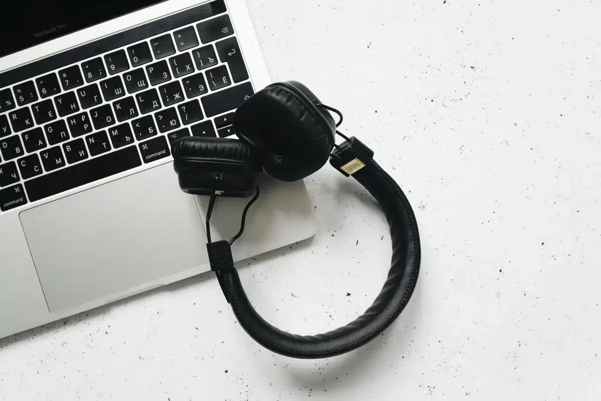 Gaming laptop with mouse and headphones on desk with monitor glow