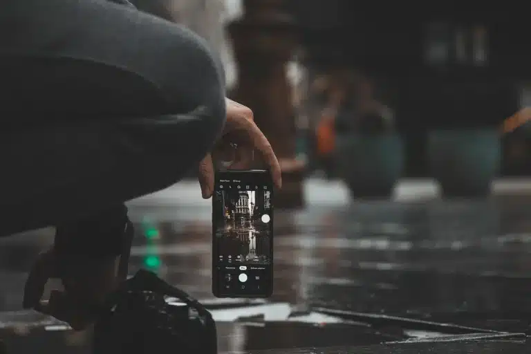 Hands holding a modern smartphone displaying its screen and design details in a tech setting
