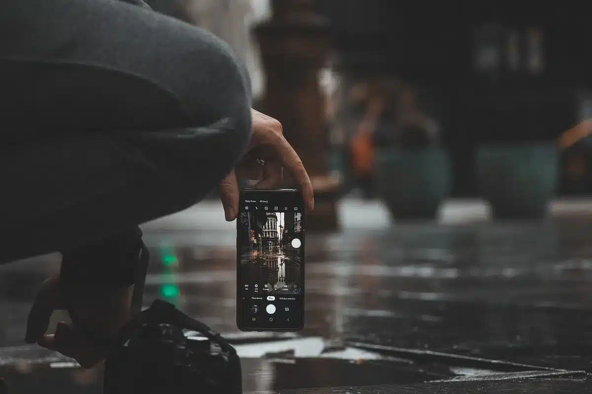 Hands holding a modern smartphone displaying its screen and design details in a tech setting