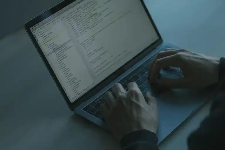 Personne tapant sur un clavier d'ordinateur portable avec des alertes de sécurité à l'écran dans un environnement de bur