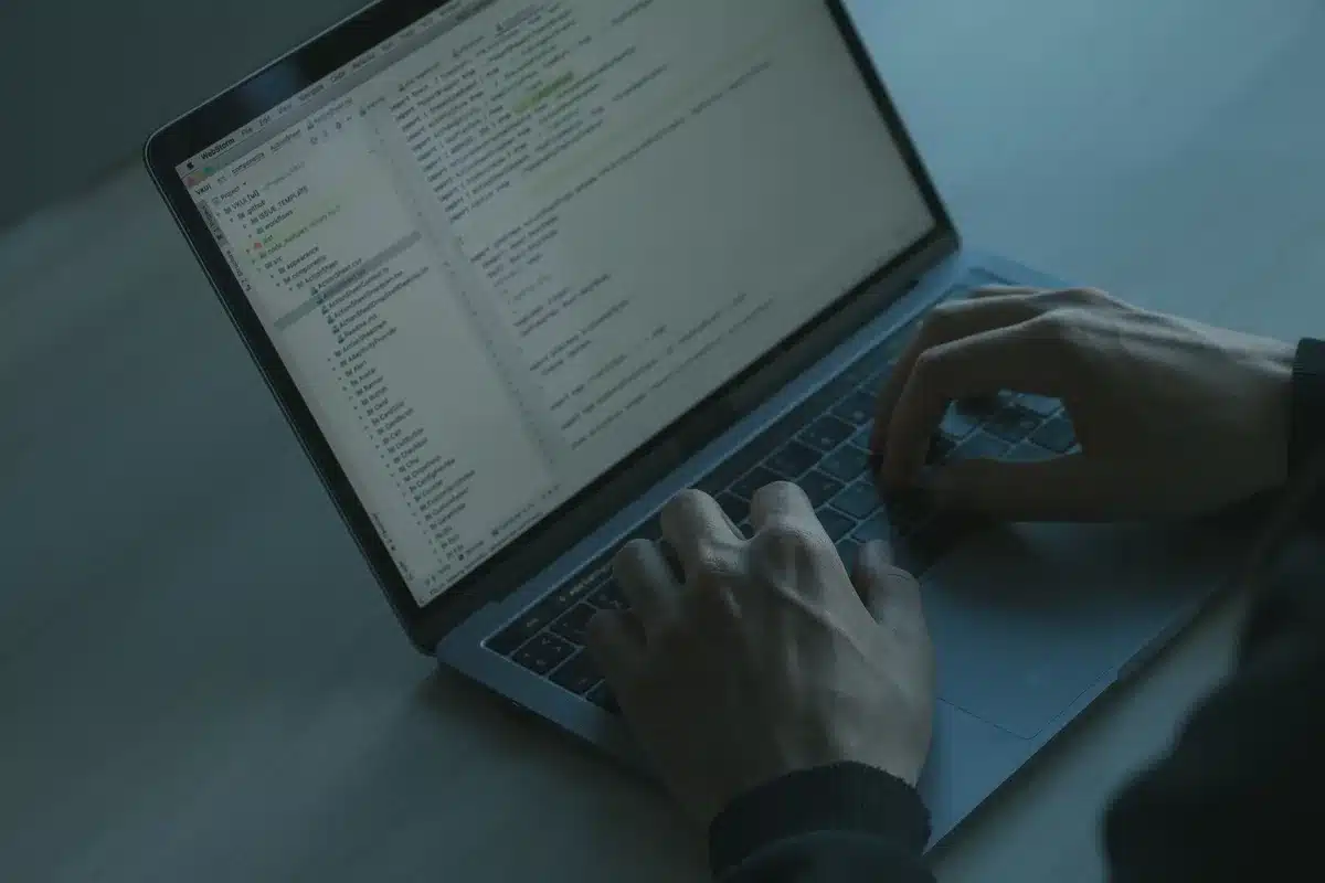 Personne tapant sur un clavier d'ordinateur portable avec des alertes de sécurité à l'écran dans un environnement de bur