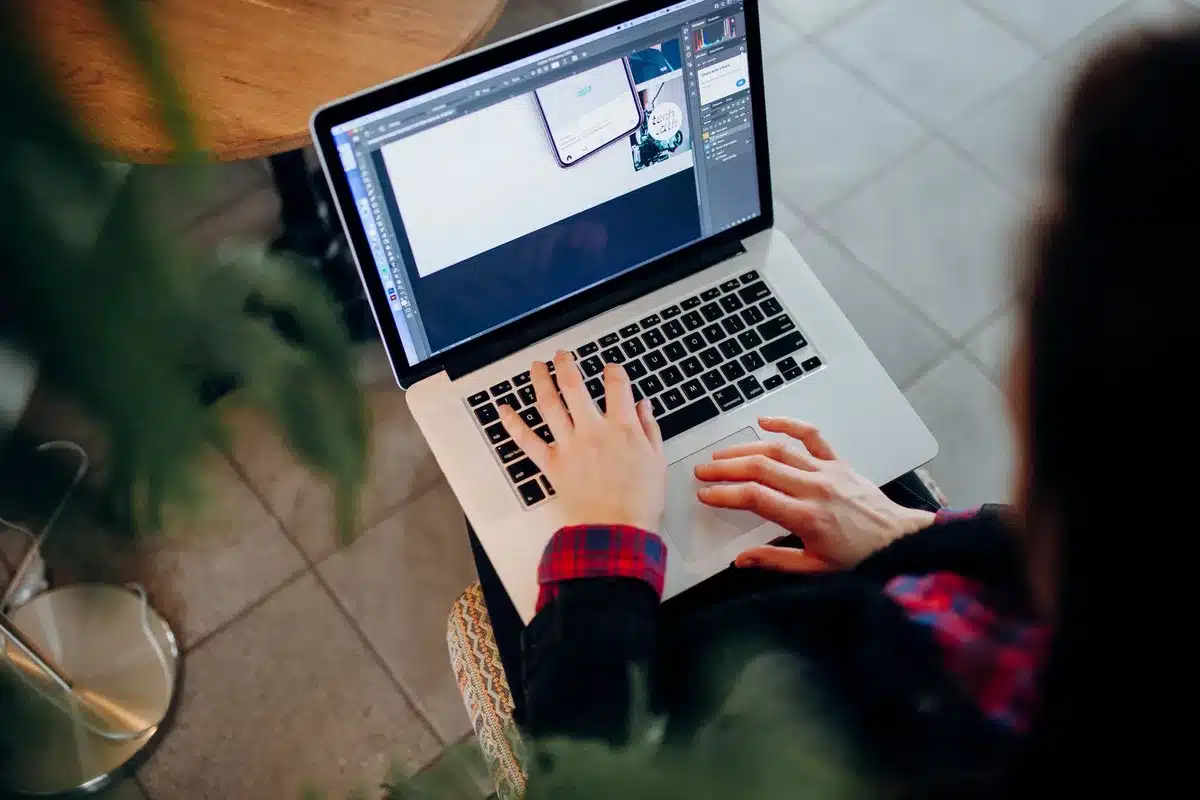 Designer working on photo editing software with adjustment layers and AI tools visible on screen