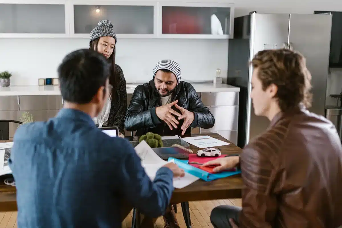 Deux hommes en costume discutant autour d'une table avec des graphiques financiers.