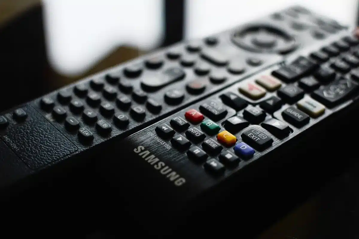 Black plastic TV stand with two-part assembly structure, centered below a large television screen