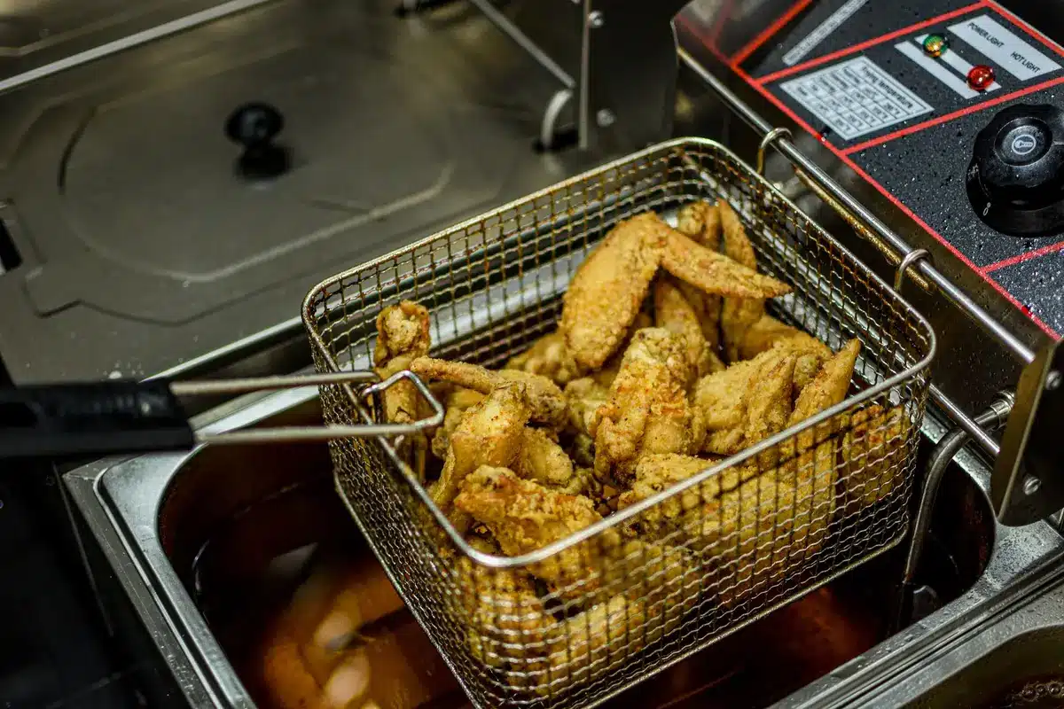 Two separate baskets in an air fryer each containing different types of food being cooked simultaneously