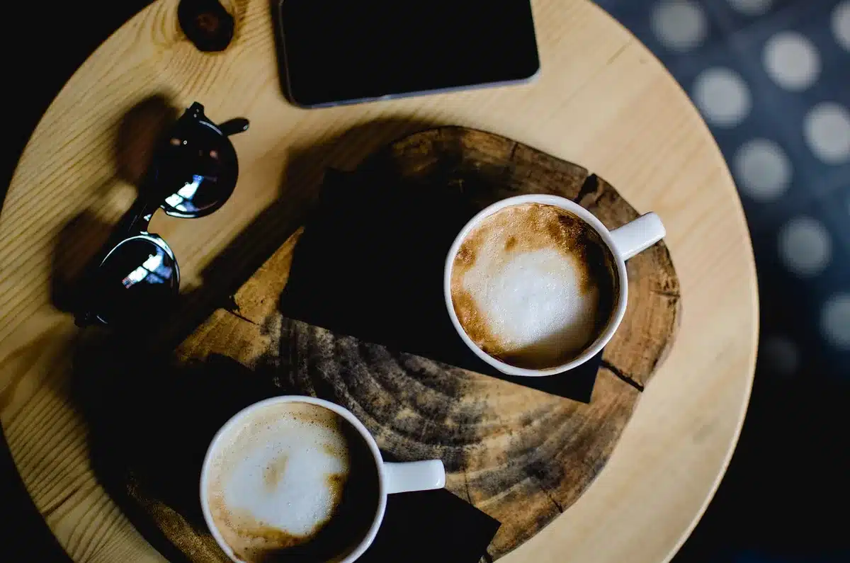 Person using a tablet while studying at a bright table with coffee