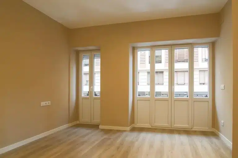 Robot vacuum and vertical cleaning station on a wooden floor near a sofa in daylight