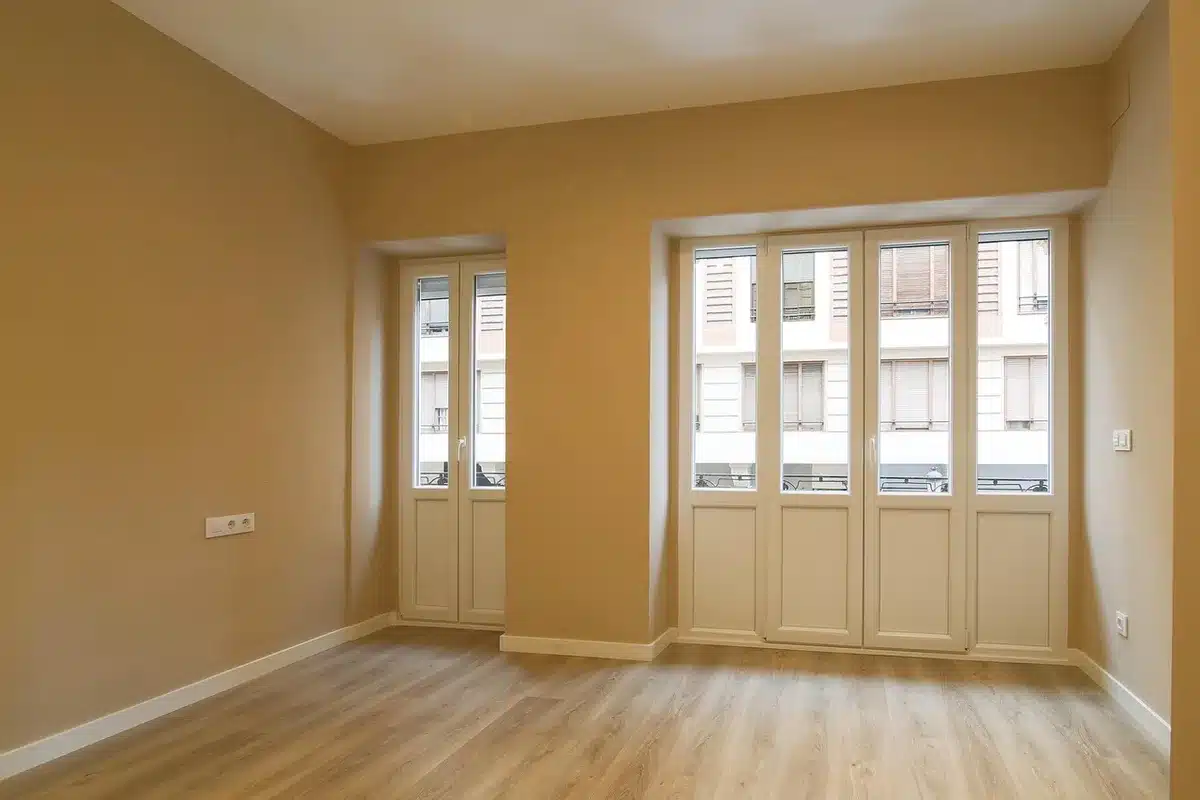 Robot vacuum and vertical cleaning station on a wooden floor near a sofa in daylight