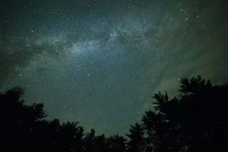 Compact smart telescope held up against a night sky full of stars and constellations
