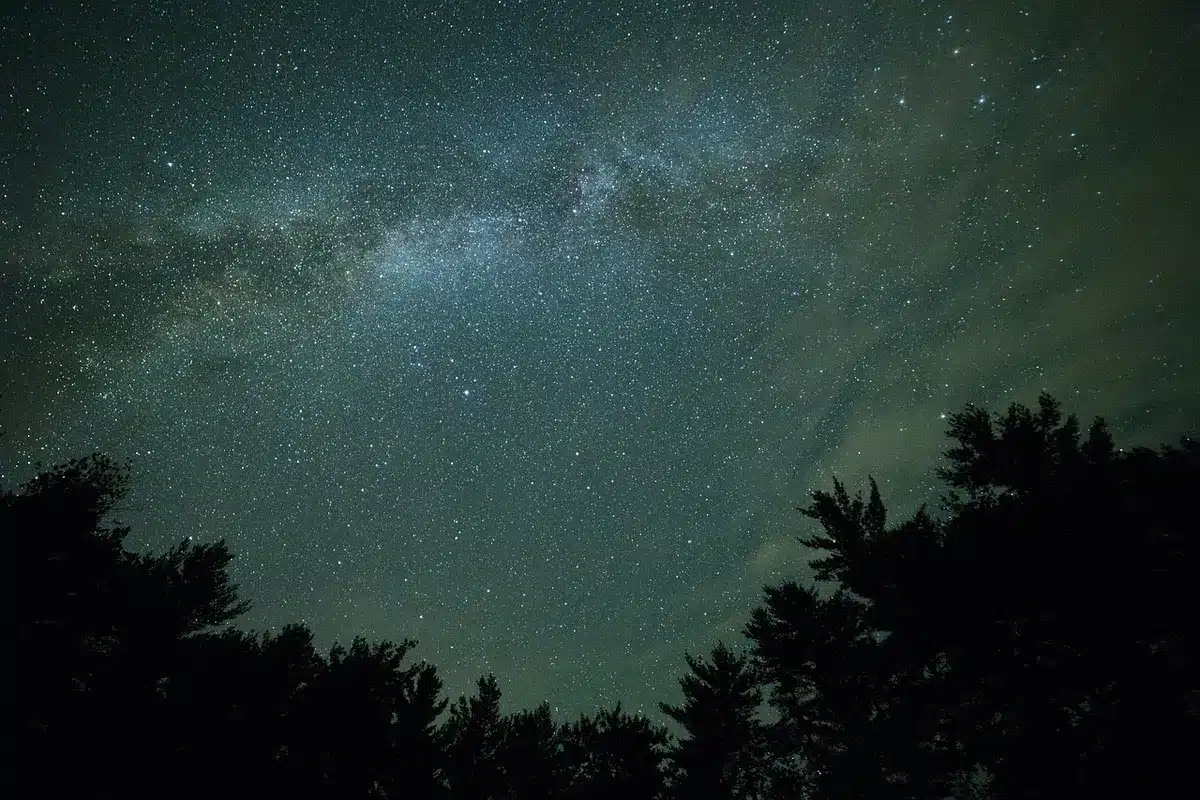 Compact smart telescope held up against a night sky full of stars and constellations