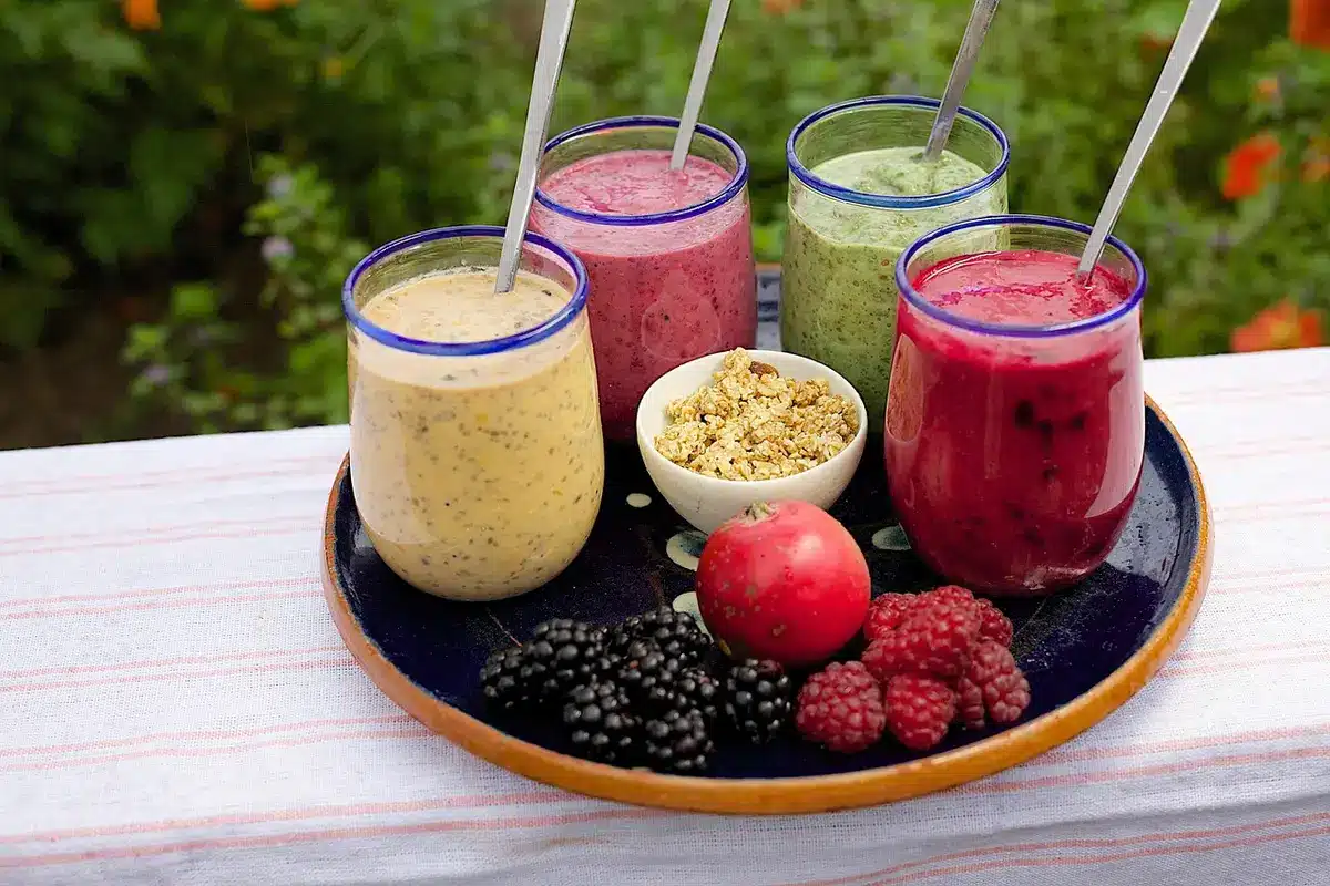 Fresh smoothie and crushed ice beside a blender on a bright kitchen counter