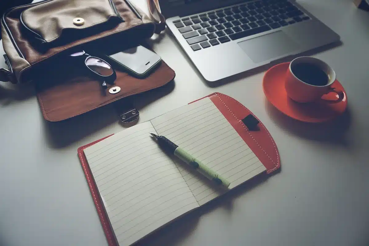 Bureau en journée près d'une grande fenêtre, ordinateur portable et checklist sur le bureau