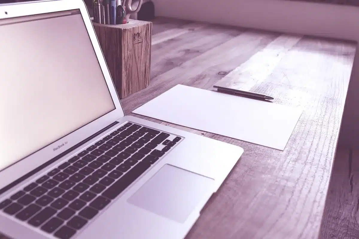 Laptop and papers on a bright desk showing a generic invoice layout