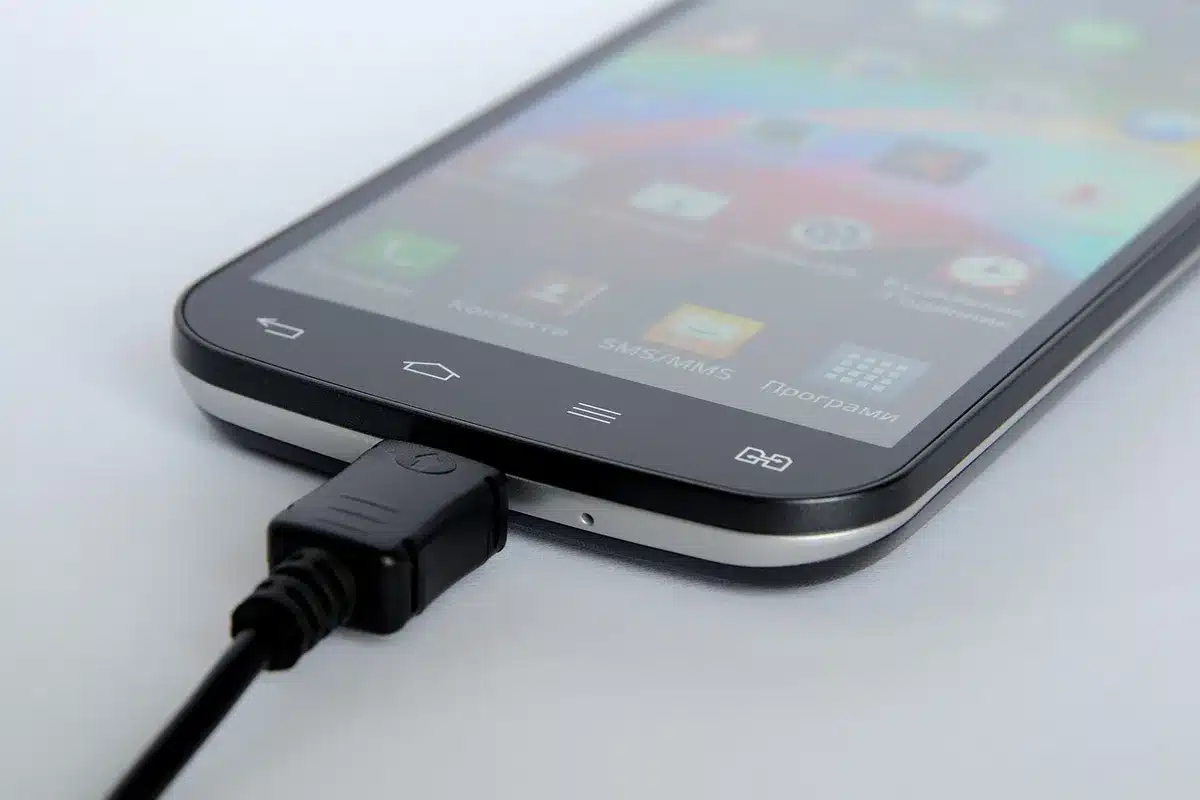 Phone on a table displaying battery test results next to a charger