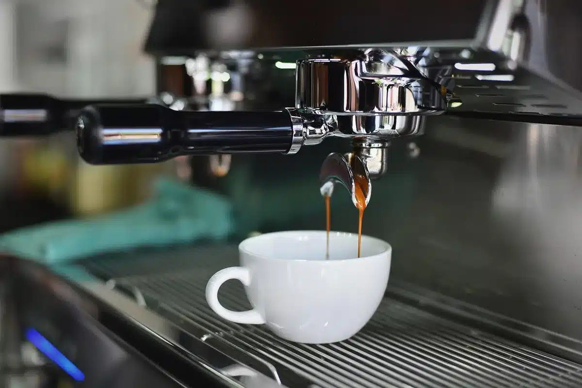 Close-up of a tamper, portafilter and small espresso shot glass on a counter