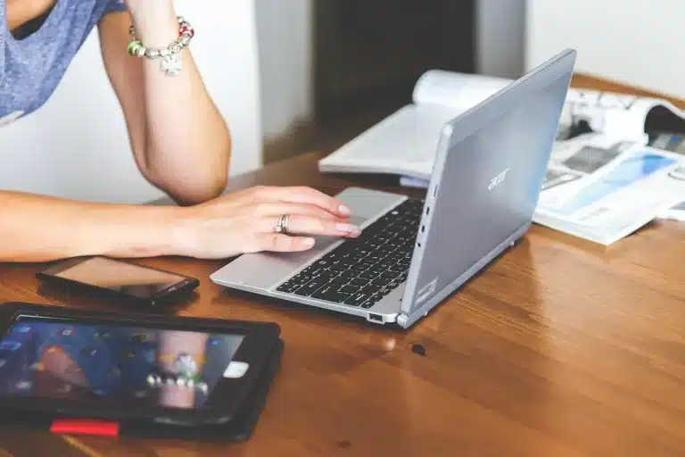 Smartphone on a bright desk next to papers and an aluminum case in daylight